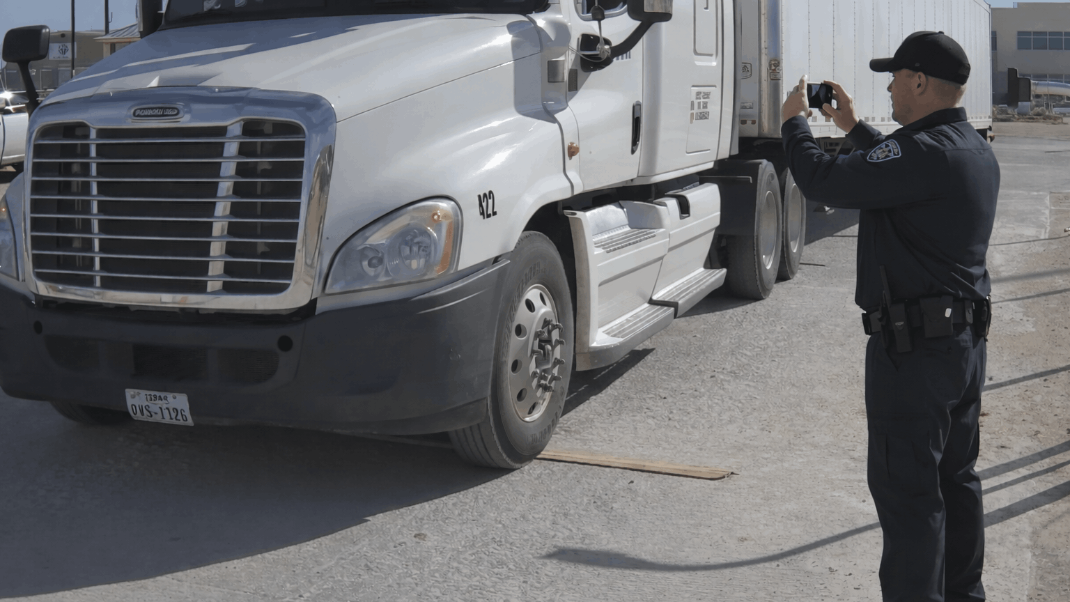 A security guard manually capturing photos of vehicles